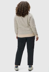 Felpa beige chiaro con piccoli pois colorati, polsini e orlo a coste. Abbinata a pantaloni larghi scuri e sneakers.