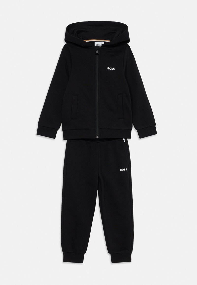 Conjunto de hoodie e calças de fato pretas feitas de um tecido macio. O hoodie apresenta um fecho zipper e bolsos, ambas as peças têm um pequeno logotipo branco "BOSS".