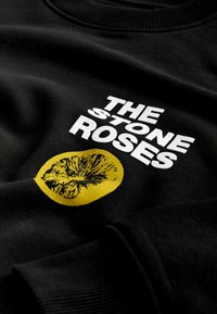 Sort sweatshirt med hvid tekst, der siger "THE STONE ROSES", og en gul cirkel med et sort lime skiver grafik. Glat stofstruktur.