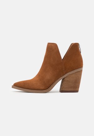 Brown suede ankle boot with a pointed toe, v-cut sides, and a stacked wooden heel. Features a zipper at the back for easy wear.