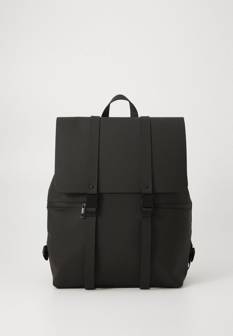 Mochila negra hecha de material duradero con cierre de solapa, dos correas ajustables y bolsillo con cremallera en la parte frontal. Diseño minimalista.