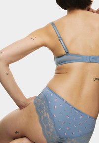 Svetle modrý spodní prádlo se květinovými vzory a krajkovými akcenty. Materiál vypadá hladce s jemnou texturou, která zvýrazňuje detail designu.