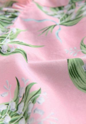 Tessuto floreale con foglie verdi e fiori bianchi su uno sfondo rosa, che mostra una texture liscia e motivi intricati.