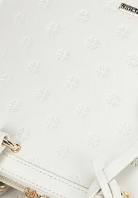 Witte leren handtas met een reliëf kruispatroon, gouden hardwareaccenten en een textuurafwerking. Voorzien van een ritssluiting en een verstelbare schouderriem.