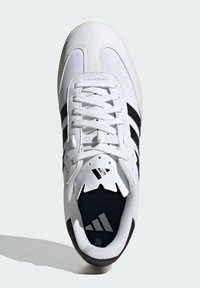 Białe sportowe buty z siateczkowej i syntetycznej cholewki, trzy czarne paski, wyściółka na kołnierzu oraz gumowa podeszwa. Logo na języku i wkładce.