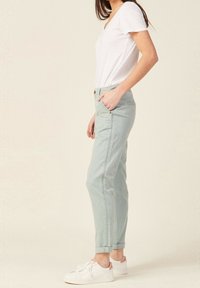 Ljusgröna bomullsbyxor med avslappnad passform, uppvikta fållar och sidofickor. Matchas med en vit t-shirt med v-ringning och vita sneakers.