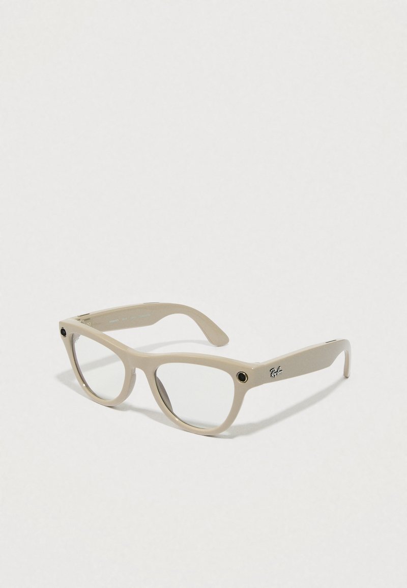 Beige rektangulære briller med transparente linser, prydet med en sort accent foran og et metallisk logo på siden. Mat overflade.