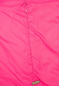 Pink jacket with a smooth, lightweight fabric. Features a central zipper and a metallic logo tag near the hem. Even texture throughout.