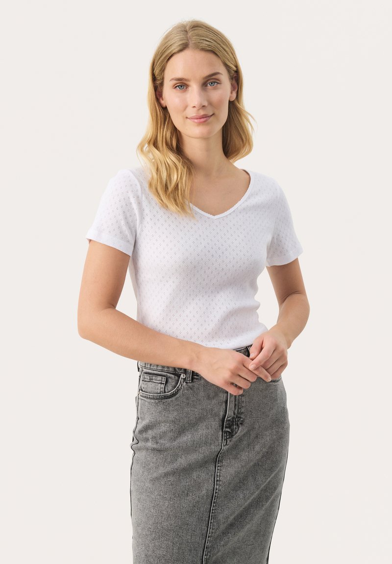 Witte shirt met korte mouwen en V-hals, met een gestructureerd patroon. Gecombineerd met een hoog getailleerde grijze denimrok.