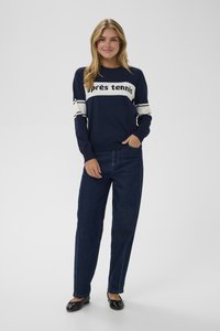 Námořnický svetr s nápisem "après tennis", bílé pruhy na rukávech, spárovaný s vysoce pasovými tmavými džíny a černými balerínami.