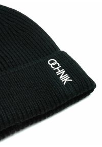 Czarna dziana czapka beanie o prążkowanej strukturze i złożonym mankieciku. Posiada białe haftowane logo na mankiecie.
