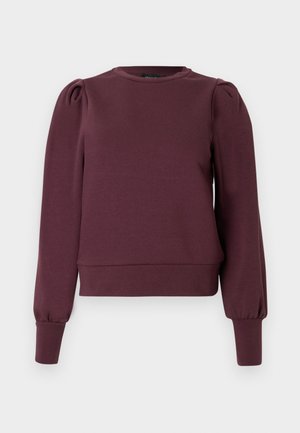 Bordó pulóver hosszú, pöttyös ujjakkal és bordázott mandzsettákkal. Puha anyag, kerek nyakkivágás és testhez simuló szegély. Sima textúra.