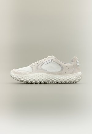 Witte en lichtgrijze lage sneaker met gestructureerde zool, veterontwerp en ademende meshpanelen tegen een neutrale achtergrond.