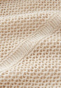 Tissu tricoté en beige clair avec un motif en maille ouverte, présentant une texture lisse et une bande de tricot plus large traversant le centre.