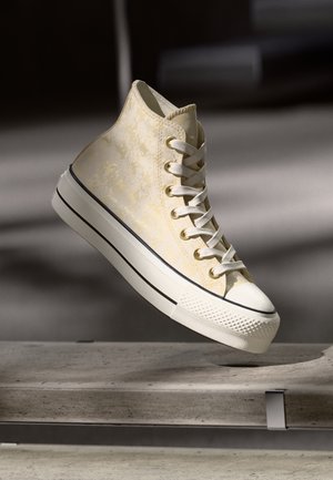 Korkeapohjaiset tennarit, joissa on tekstuuri heledad kollane ülemine osa, valge kummine varbakate ja kontrastsed mustad triibud valgel tallal. Paelaga sulgemine.