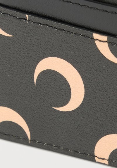 Čierny textúrovaný materiál s opakujúcim sa vzorom polmesiacov v bledo ružovej farbe. Viditeľné šitie pozdĺž okrajov.