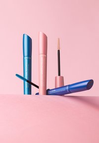 Cuatro máscaras con tubos de colores: azul (resistente al agua), rosa (longitud y volumen) y azul oscuro (rizado). Las brochas tienen formas y tamaños variados.
