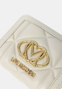 Portafoglio in ecopelle bianca trapuntata con logo Love Moschino dorato e design a cuore, caratterizzato da cuciture evidenti e una superficie liscia.