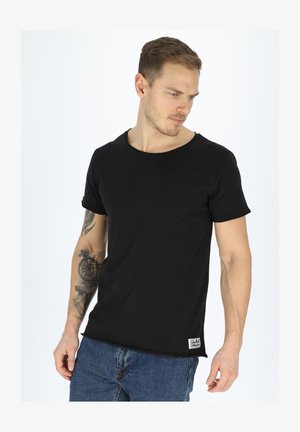 Zwarte katoenen t-shirt, ronde hals, korte mouwen. Heeft een klein logolabel aan de onderzijde links. Draag het met blauwe denim jeans.