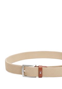 Ceinture tissée beige avec une finition texturée, dotée d'une boucle en métal argenté et d'un accent en cuir marron avec une étiquette de logo.