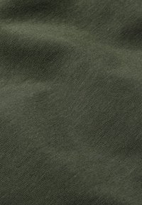 Tessuto verde scuro con una consistenza morbida e un leggero motivo tessuto, che mostra una moderata elasticità e una finitura opaca.