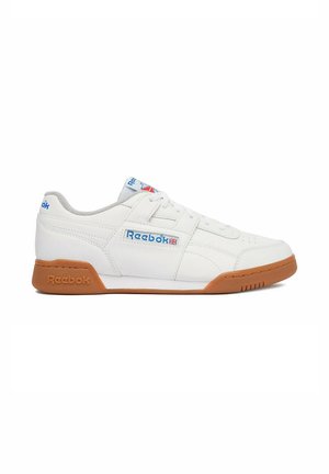 Zapatilla blanca Reebok de corte bajo con suela de goma, logotipo azul de Reebok en el lateral, la lengüeta y el talón, y cierre de cordones.