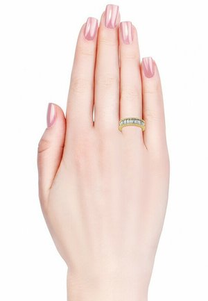Goldring mit einer Reihe kleiner, klarer Steine. Eine Hand mit hellrosa Nagellack präsentiert den Ring vor einem schlichten weißen Hintergrund.