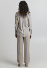 Leichtes beige- und blaugestreiftes Hemd und weite Hose, mit langen Ärmeln, Knopfmanschetten und einer lockeren Passform.