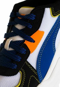 Sneaker con tomaia in mesh con accenti bianchi, neri, blu e arancioni. Materiale nero testurizzato, striscia blu audace e lacci a contrasto.