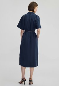 Vestito blu navy con maniche corte, vita con cintura e orlo fino al ginocchio. Tessuto morbido con una superficie liscia e design della schiena con dettagli minimi.