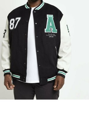 Mann trägt schwarze und weiße College-Jacke mit grün-weiß gestreiftem Kragen und Bündchen, mit den Aufnähern "87" und großem grünem "A."