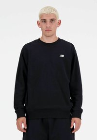 Zwarte crewneck sweatshirt van zacht materiaal, met een klein wit logo op de linkerkant van de borst en geribbelde manchetten en zoom.