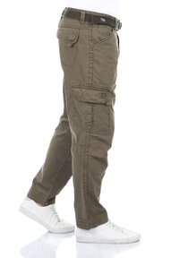 Olivgrüne Cargo-Hose mit mehreren Taschen, Gürtelschlaufen und schmaler geschnittenen Beinen. Hergestellt aus strapazierfähigem Stoff mit leicht zerknitterter Textur.