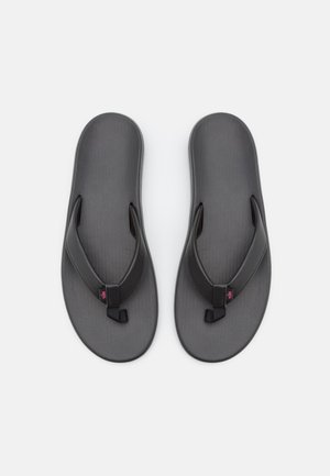 Chanclas negras con una plantilla texturizada, correas de goma suave y un acento rosa en la correa. Diseño ligero y plano, adecuado para el uso casual.