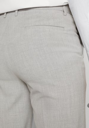 Pantaloni sartoriali grigio chiaro realizzati in tessuto strutturato, con una tasca posteriore singola e cuciture pulite.