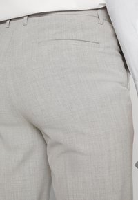 Light gray tailored trousers made from a textured fabric, featuring a flat front, side pockets, and a single back pocket.