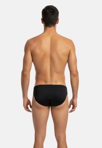 Boxers de bain noirs vus de dos, fabriqués en tissu lisse avec un ajustement serré et un design simple et épuré. Pas de motifs ni d'accents.
