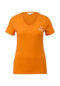 T-shirt orange à manches courtes en coton. Présente un décolleté en scoop et un graphique sur la poitrine gauche avec du texte et une icône stylisée.