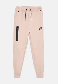 Ljust rosa Nike sweatpants med svarta dragsnoddar, en ficka med dragkedja på vänster lår, och elastiska muddar vid anklarna.