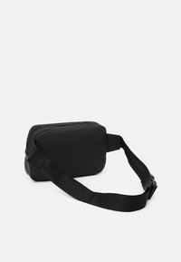 Bolso cruzado rectangular negro hecho de tela suave, con cierre de cremallera y correa ajustable de cinta.