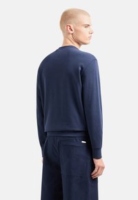 Felpa blu navy con collo a giro, polsini a costine, realizzata in morbido tessuto misto cotone; presenta un orlo dritto e un design minimalista.