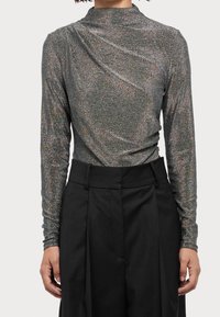 Langarmshirt aus metallic silbernem Stoff mit bunten Funkeln. Figurbetontes Design mit hohem Kragen und Raffung im Rücken.