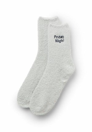 Chaussettes en peluche gris clair avec des poignets côtelés et une surface texturée. Présente le texte "Friday Night" en bleu marine sur une chaussette.