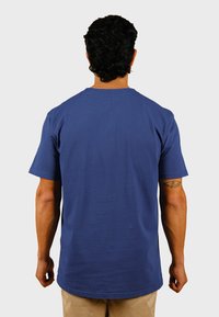 Kortärmad blå bomullströja med rund hals och rak fåll. Har en liten etikett på baksidan och en slät yta.