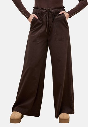 Szerokie spodnie z ciemnego brązowego bawełnianego materiału, z wysokim stanem, sznurkiem do regulacji oraz przednimi kieszeniami naszytymi. Tkanina jest gładka z delikatnym połyskiem.