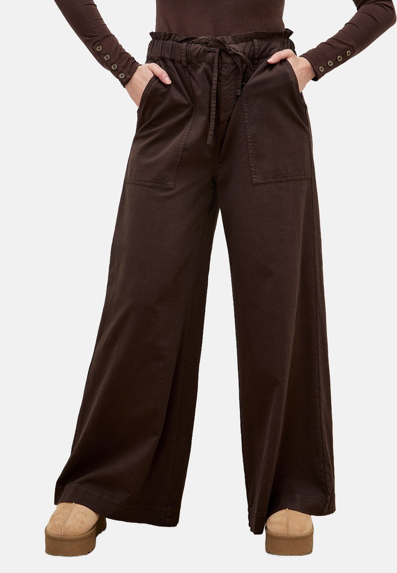 Wijdvallende, donkerbruine katoenen broeken met een hoge taille, een trekkoord en voorzakken. De stof is glad met een lichte glans.