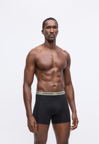 Fekete boxer alsónadrág puha, rugalmas derékpánttal, amelyen egy világosszürke "BJÖRN BORG" logó található. Az anyag simának és testhez állónak tűnik.