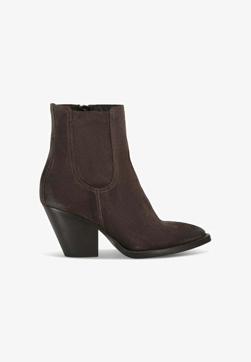 Stivale alla caviglia in suede marrone con punta affusolata, pannelli laterali elastici e tacco spesso nero. Texture liscia con dettagli di cucitura sottili.