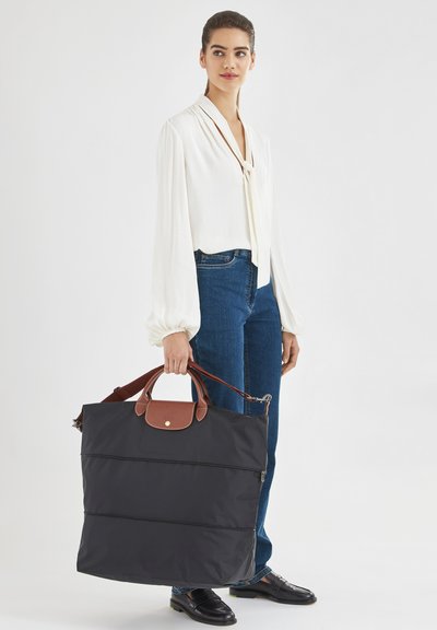 Schwarze Nylon-Shopper-Tasche mit braunen Lederakzenten, doppelten Griffen und Reißverschluss. Große, rechteckige Form mit glatter Textur.