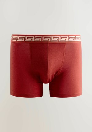 Bordó boxer alsónemű, bézs színű, görög kulcs mintával díszített derékszíjjal. Simaság jellemzi, és kényelmes, testhezálló fazonban készült.